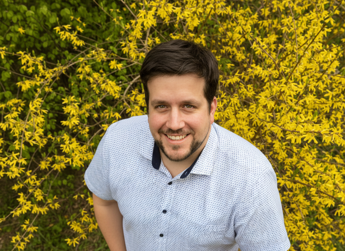 Mediator Norbert Becker von oben vor einer gelb blühenden Hecke fotografiert